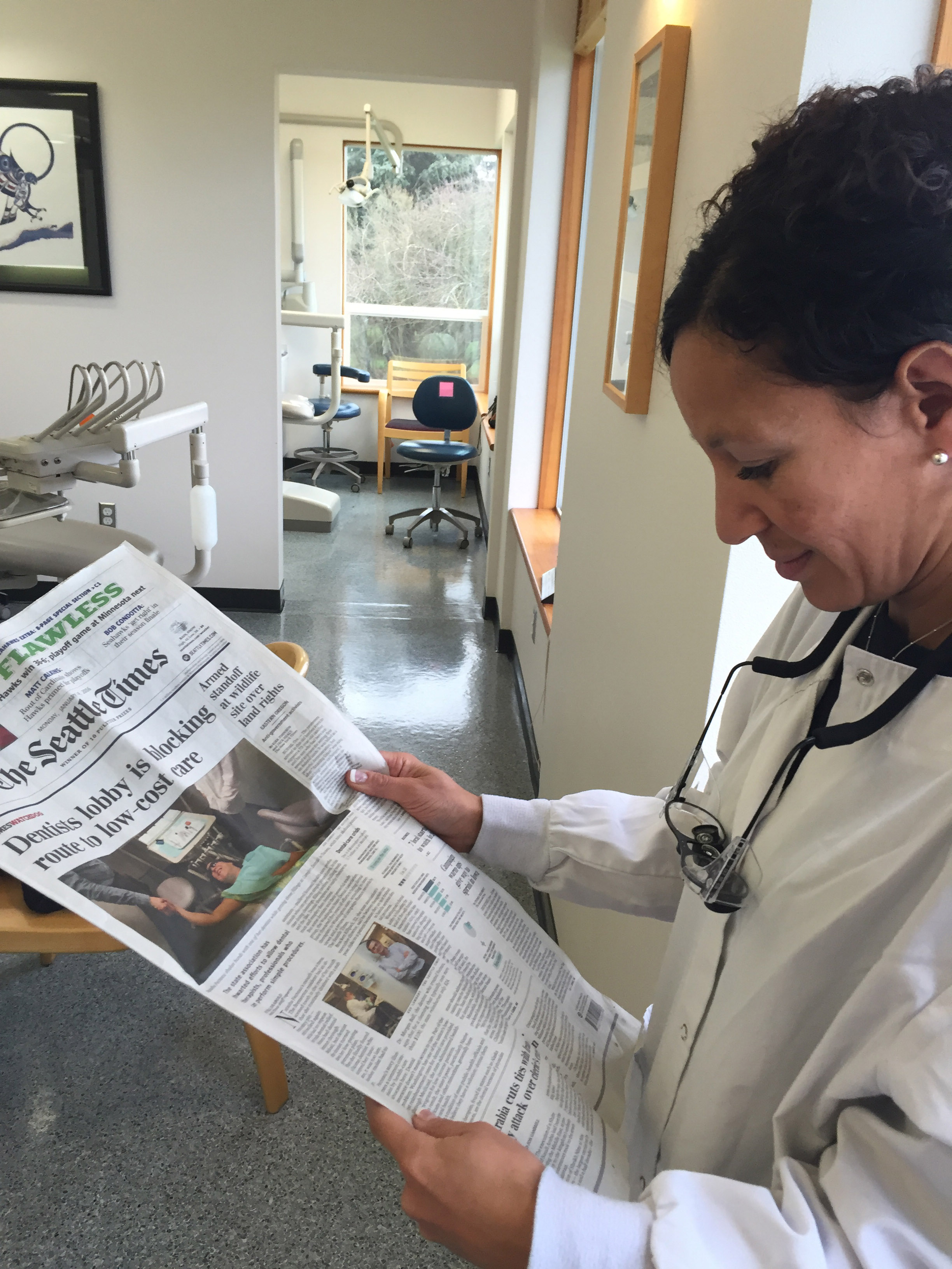 Dr Rachael Hogan, supervising dentist at the Swinomish tribal dental clinic, reads the February Seattle Times story detailing the tribe's innovative use of dental therapists.