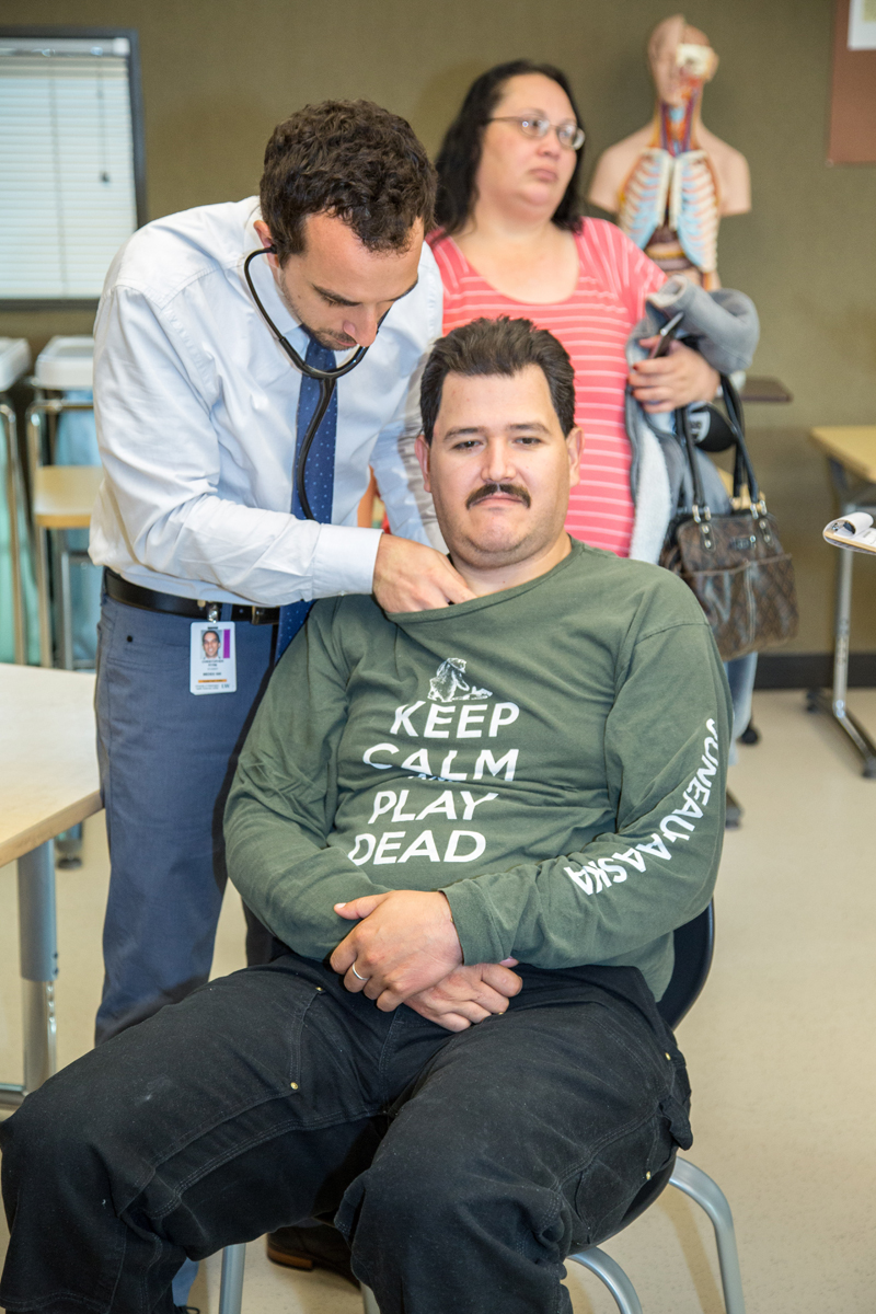 MEDEX PA student Chris Pitre of Seattle Class 50 listens to a patient's heart during a preliminary health screening.