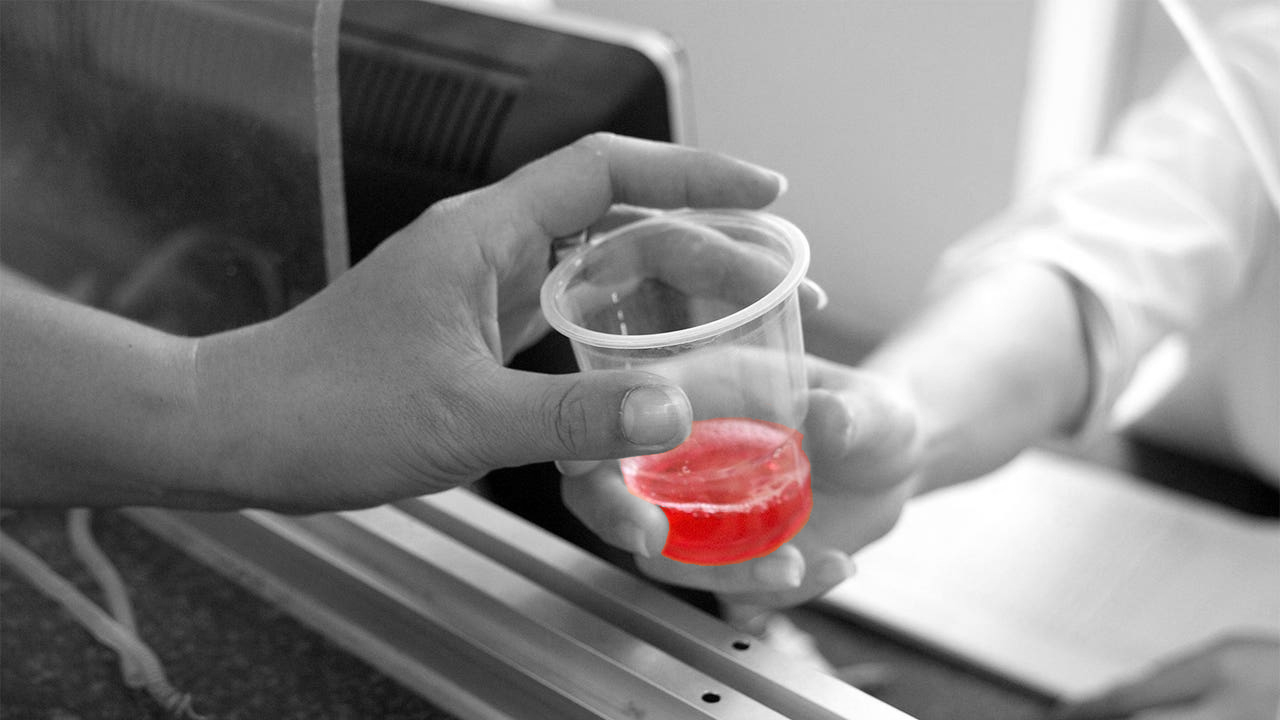 Black and white image with red color highlighted of pharmacist dispensing methadone to a patient